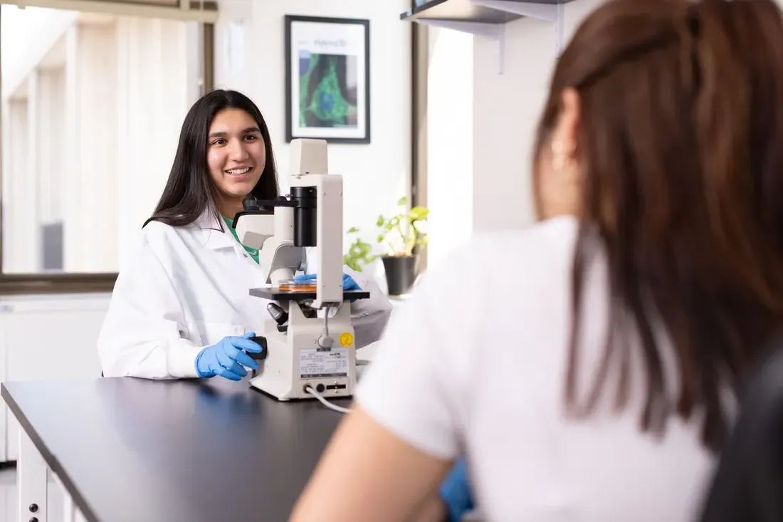 Person sitting with a microscope.